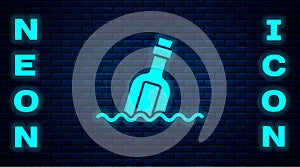 Glowing neon Glass bottle with a message in water icon isolated on brick wall background. Letter in the bottle. Pirates