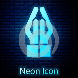 Glowing neon Hands in praying position icon isolated on brick wall background. Prayer to god with faith and hope. Vector