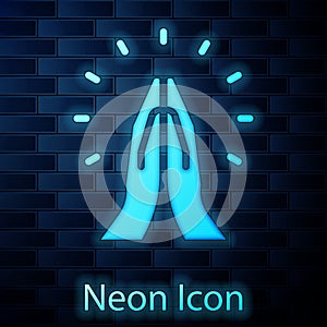 Glowing neon Hands in praying position icon isolated on brick wall background. Prayer to god with faith and hope. Vector