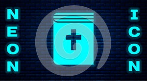 Glowing neon Holy bible book icon isolated on brick wall background. Vector