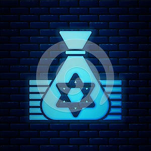 Glowing neon Jewish money bag with star of david icon isolated on brick wall background. Currency symbol. Vector