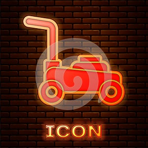 Glowing neon Lawn mower icon isolated on brick wall background. Lawn mower cutting grass. Vector