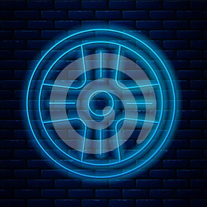Glowing neon line Alloy wheel for a car icon isolated on brick wall background. Vector
