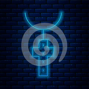 Glowing neon line Christian cross on chain icon isolated on brick wall background. Church cross. Vector