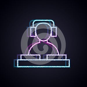 Glowing neon line DJ wearing headphones in front of record decks icon isolated on black background. DJ playing music