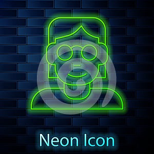 Glowing neon line Hacker or coder icon isolated on brick wall background. Programmer developer working on code, coding