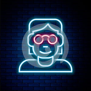 Glowing neon line Hacker or coder icon isolated on brick wall background. Programmer developer working on code, coding