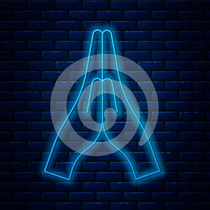 Glowing neon line Hands in praying position icon isolated on brick wall background. Prayer to god with faith and hope