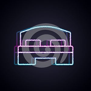 Glowing neon line Hotel room bed icon isolated on black background. Vector