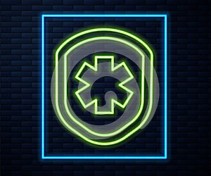 Glowing neon line Medical shield with cross icon isolated on brick wall background. Protection, safety, password