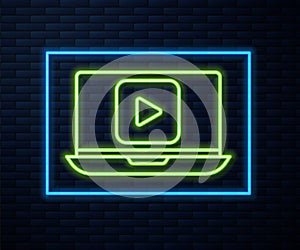 Glowing neon line Online play video icon isolated on brick wall background. Laptop and film strip with play sign. Vector