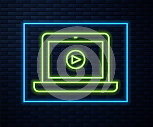 Glowing neon line Online play video icon isolated on brick wall background. Laptop and film strip with play sign. Vector
