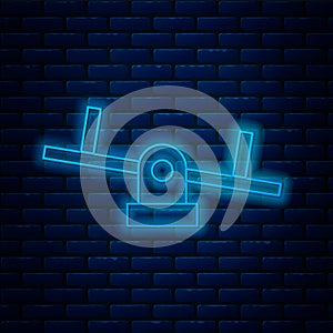 Glowing neon line Seesaw icon isolated on brick wall background. Teeter equal board. Playground symbol. Vector