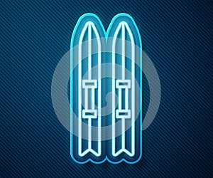 Glowing neon line Ski and sticks icon isolated on blue background. Extreme sport. Skiing equipment. Winter sports icon. Vector