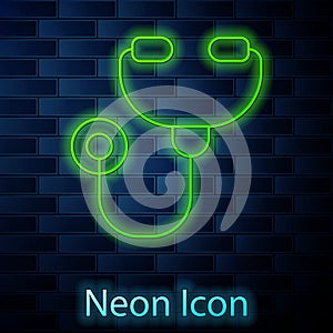 Glowing neon line Stethoscope medical instrument icon isolated on brick wall background. Vector Illustration