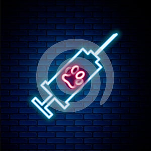 Glowing neon line Syringe with pet vaccine icon isolated on brick wall background. Dog or cat paw print. Colorful