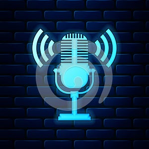 Glowing neon Microphone icon isolated on brick wall background. On air radio mic microphone. Speaker sign. Vector