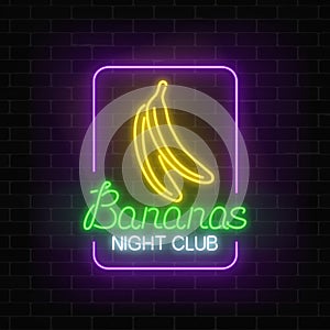 Glowing neon nightclub signboard with bananas in rectangle frame on dark brick wall background.