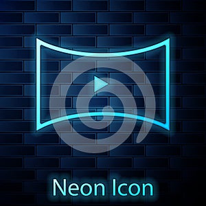 Glowing neon Online play video icon isolated on brick wall background. Film strip with play sign. Vector