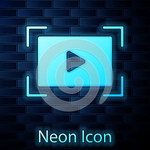 Glowing neon Online play video icon isolated on brick wall background. Film strip with play sign. Vector