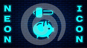 Glowing neon Piggy bank and hammer icon isolated on brick wall background. Icon saving or accumulation of money