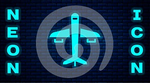 Glowing neon Plane icon isolated on brick wall background. Flying airplane icon. Airliner sign. Vector