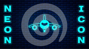 Glowing neon Plane icon isolated on brick wall background. Flying airplane icon. Airliner sign. Vector