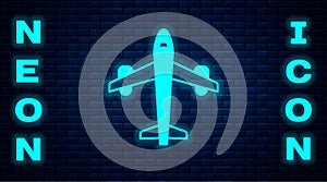 Glowing neon Plane icon isolated on brick wall background. Flying airplane icon. Airliner sign. Vector