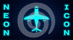 Glowing neon Plane icon isolated on brick wall background. Flying airplane icon. Airliner sign. Vector