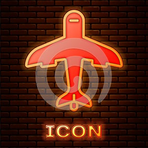 Glowing neon Plane icon isolated on brick wall background. Flying airplane icon. Airliner sign. Vector