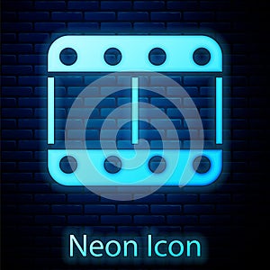 Glowing neon Play video icon isolated on brick wall background. Film strip sign. Vector