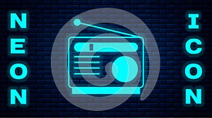 Glowing neon Radio with antenna icon isolated on brick wall background. Vector