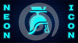 Glowing neon Roman army helmet icon isolated on brick wall background. Vector