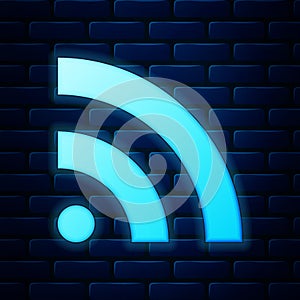 Glowing neon RSS icon isolated on brick wall background. Radio signal. RSS feed symbol. Vector