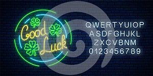 Glowing neon sign with geed luck wish and four-leaf clovers in circle frames with alphabet. Three leaves of shamrock