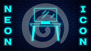 Glowing neon TV table stand icon isolated on brick wall background. Vector