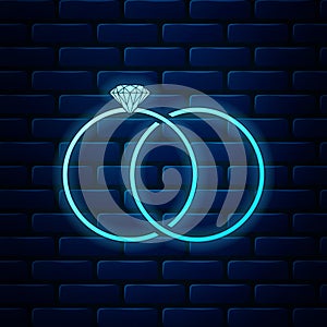 Glowing neon Wedding rings icon isolated on brick wall background. Bride and groom jewelery sign. Marriage icon. Diamond