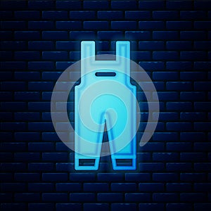 Glowing neon Work overalls icon isolated on brick wall background. Vector