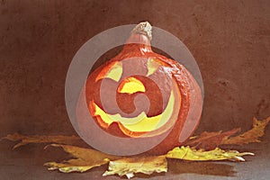 Glowing pumpkin with autumn leaves on a dark background. Jack`s Lantern. Halloween