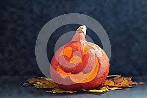 Glowing pumpkin with autumn leaves on a dark background with smoke . Jack`s Lantern. Halloween