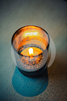 Glowing red candle set on a dark wooden table in a dimly lit room