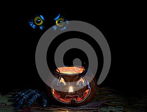 Glowing scary pumpkin decoration in darkness with owl eyes in ba