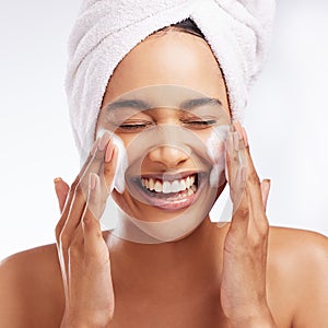 Glowing skin is something you have to maintain. Studio shot of a beautiful young woman washing her face against a white