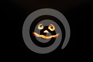 Glowing smiling face Halloween pumpkin, candle holder, isolated on night dark black background.