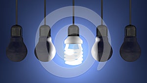 Glowing spiral light bulb among dead tungsten ones hanging on blue