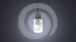 Glowing spiral light bulb hanging on gray