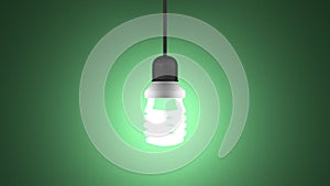Glowing spiral light bulb hanging on green
