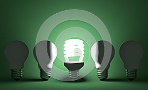 Glowing spiral light bulb in row of dead tungsten ones on green