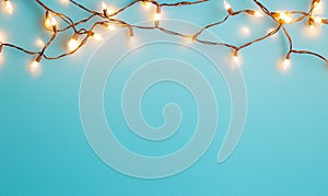 Glowing string lights on blue background, copy space for holiday design