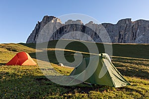 A glowing tent in the mountains under a blue morningsky. Sunrise and mountains in the background. Summer landscape. Panorama Brigh